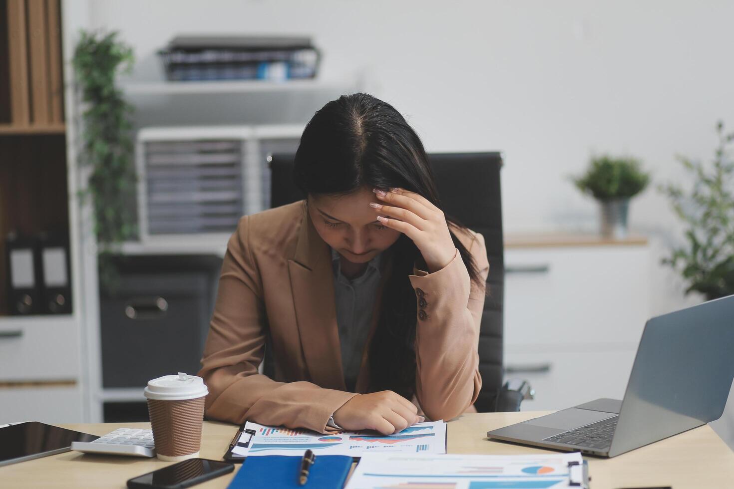 Portrait of tired young business Asian woman work with documents tax laptop computer in office. Sad, unhappy, Worried, Depression, or employee life stress concept photo