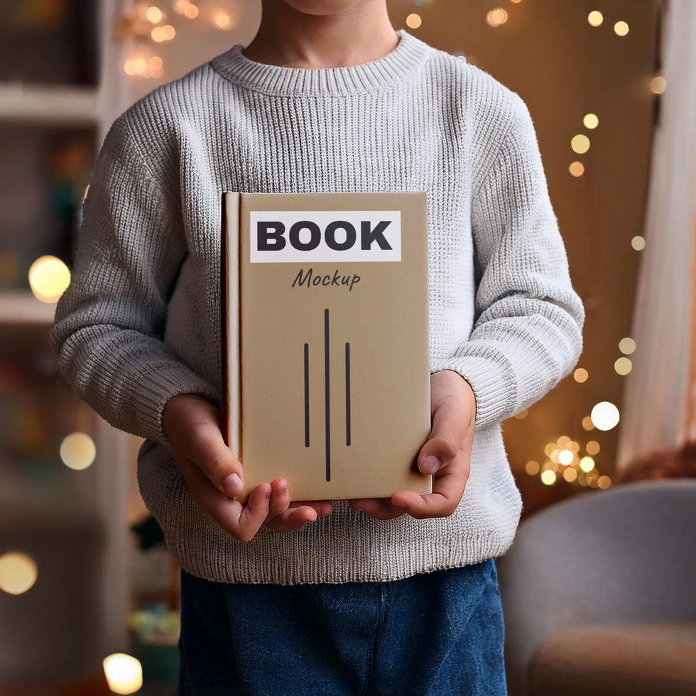 A child holding a book mockup in front of a christmas tree psd
