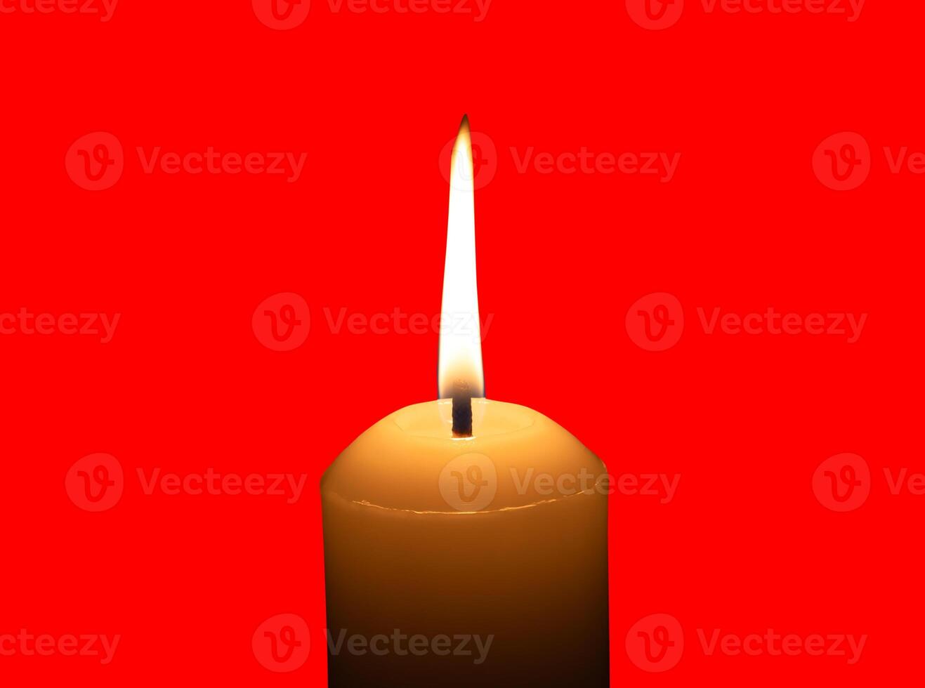 A single burning candle flame or light glowing on a big white candle isolated on red background with clipping path photo