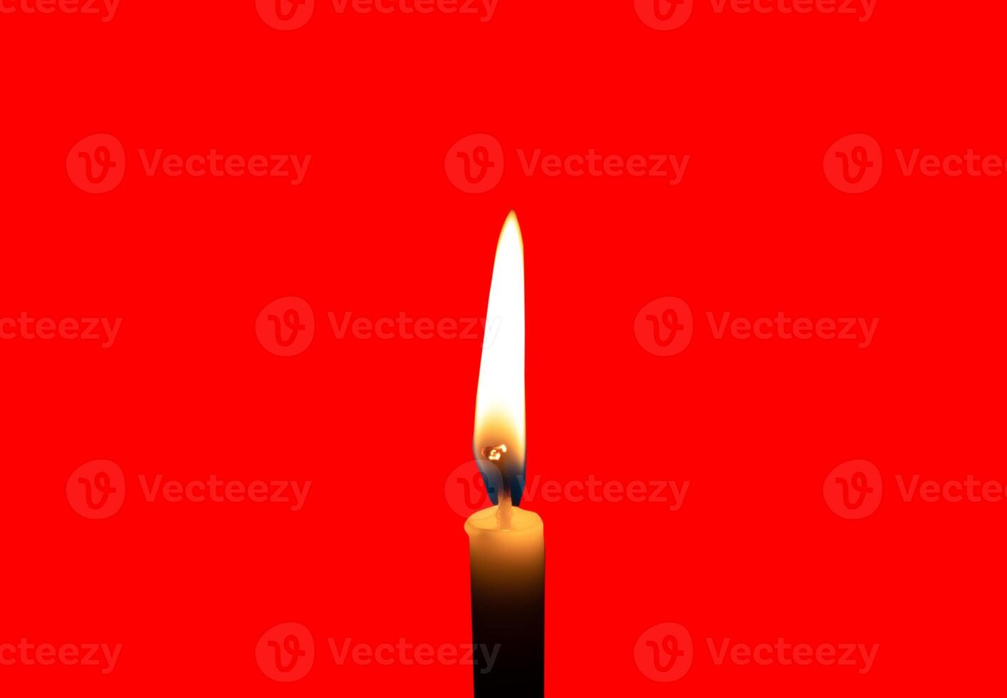A single burning candle flame or light glowing on a small white candle isolated on red background with clipping path photo