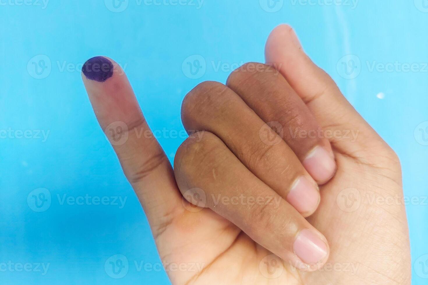 Ink marks marked by the election on the little finger with a blue background photo