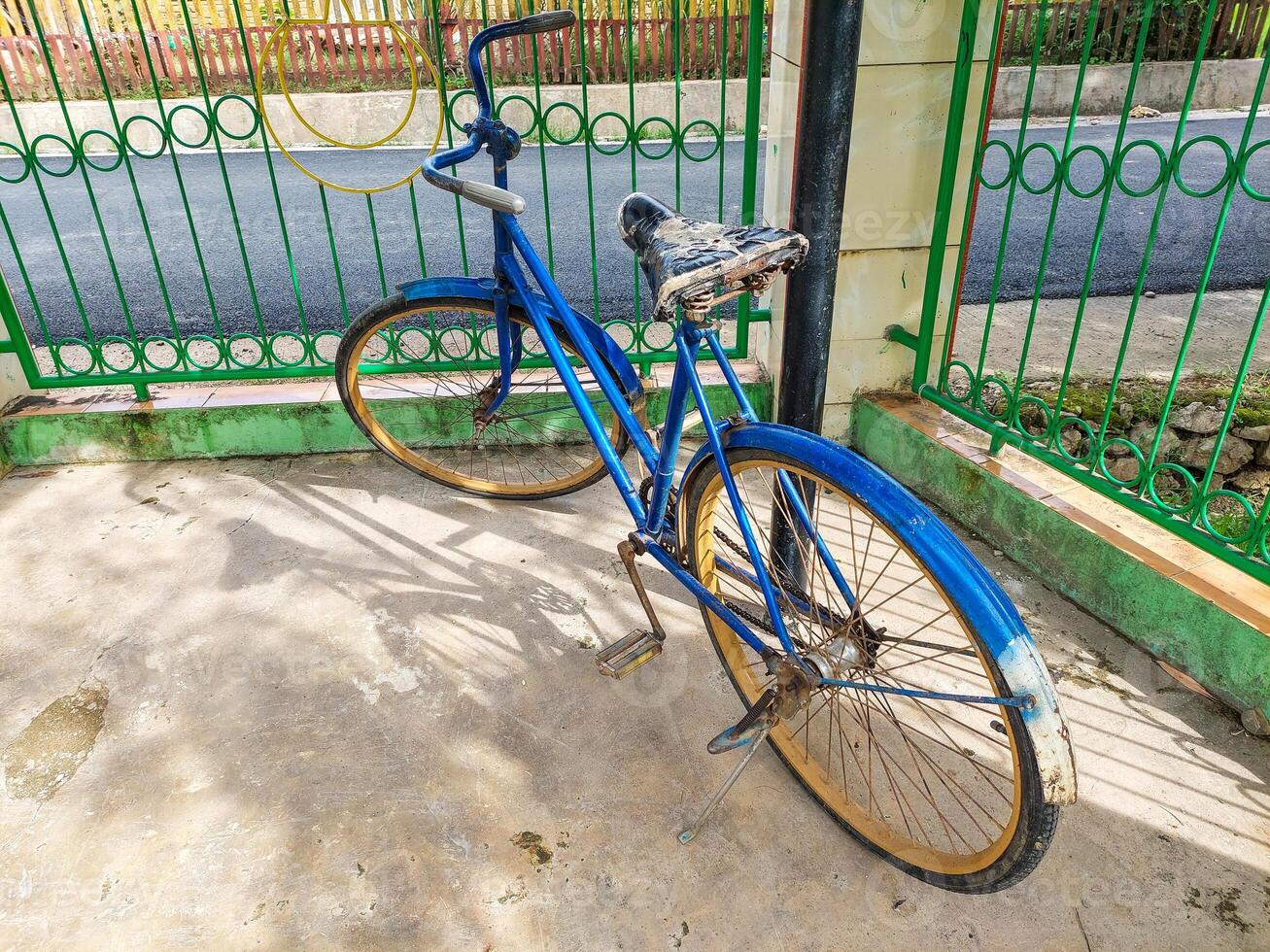 An antique bicycle was parked near the fence, an old blue bicycle photo