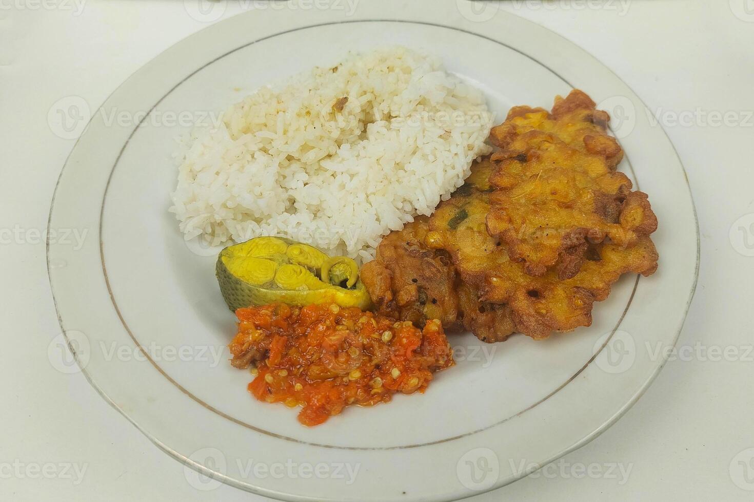 Rice mixed with fried fish and tempeh vegetables on a white plate photo