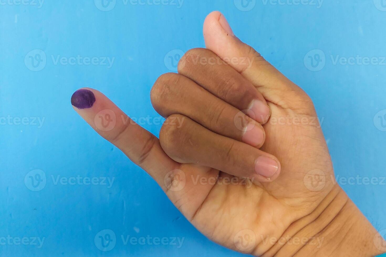 Ink marks marked by the election on the little finger with a blue background photo