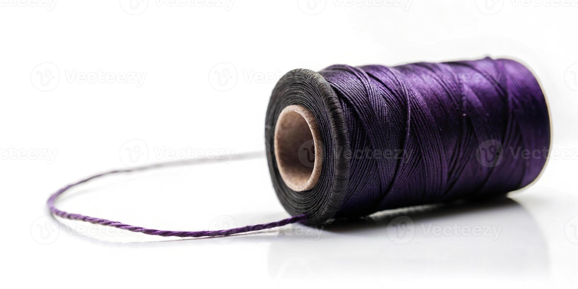 Low angle view of purple thread in black thread roll on white background. Prepare to use for sewing garment photo