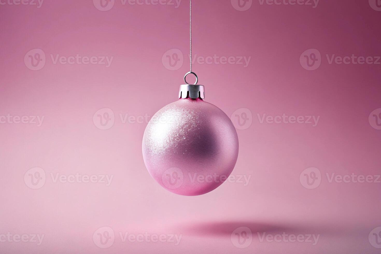 Pink Christmas ball hanging in the air on pastel background photo
