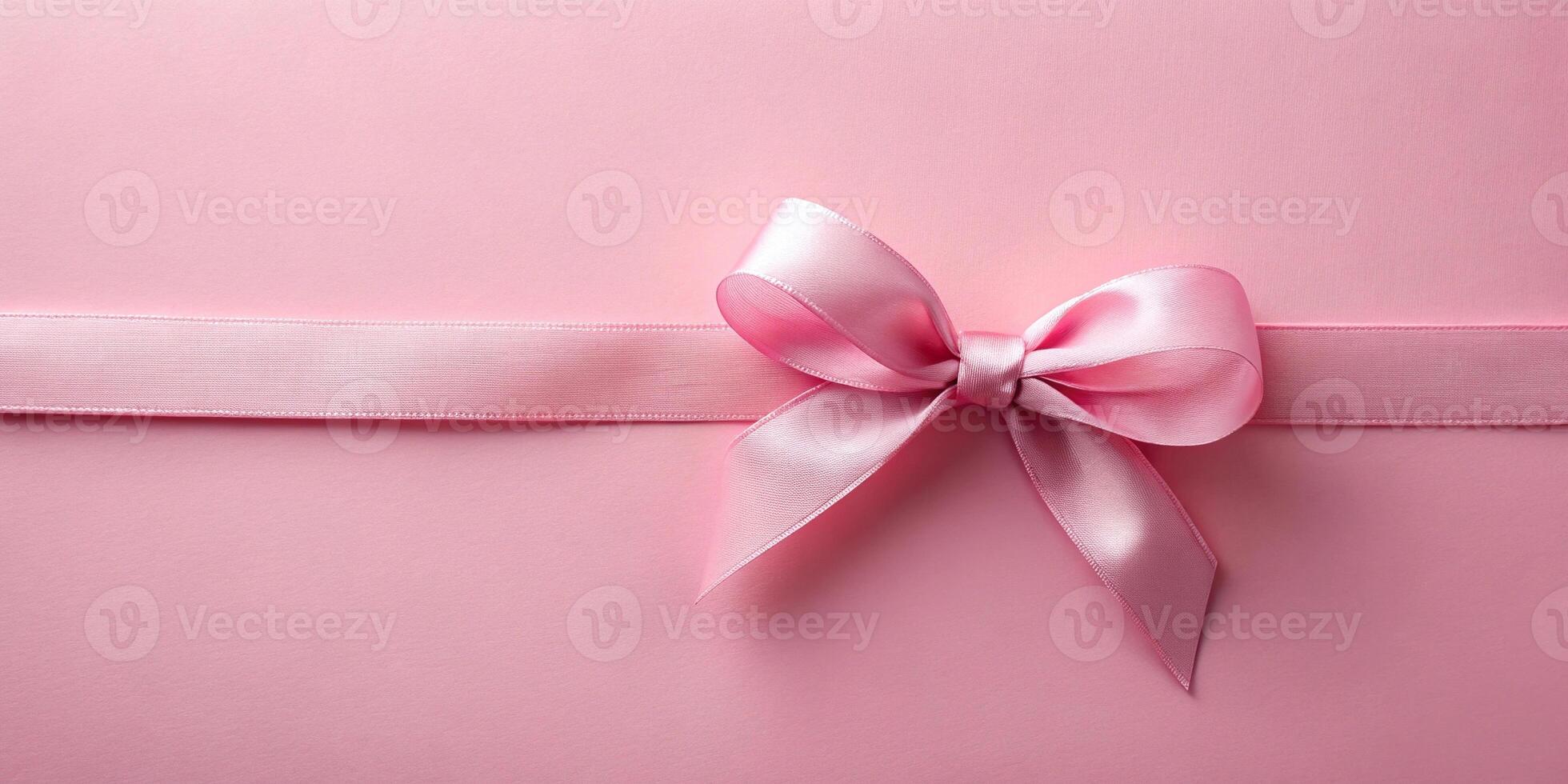 Pastel pink ribbon with bow on pink background, bird eye view photo