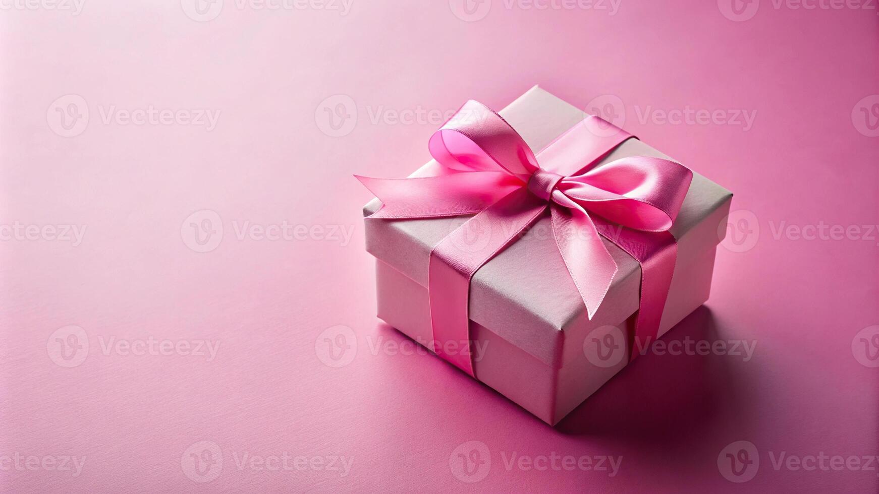 Pink gift box with ribbon on pink background in forced perspective photo