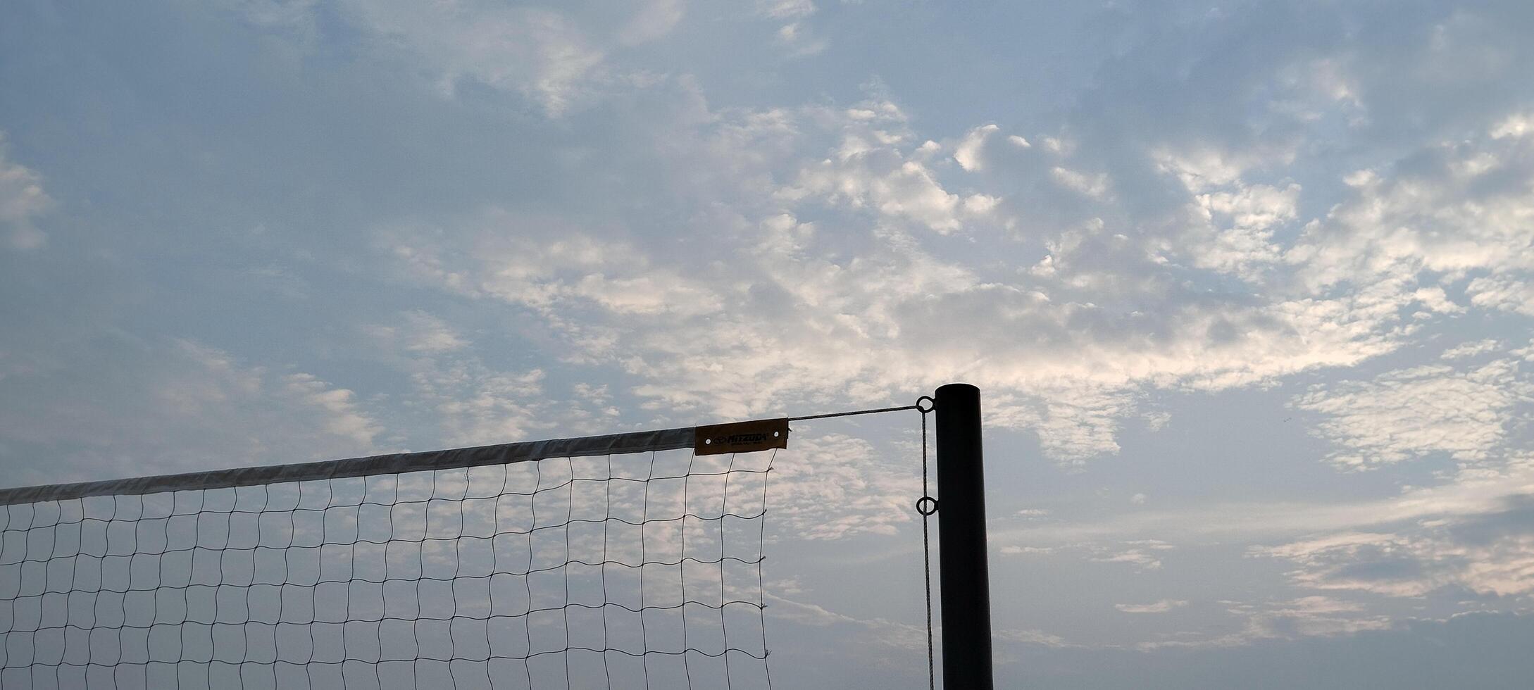 A volleyball net is shown against a cloudy sky photo