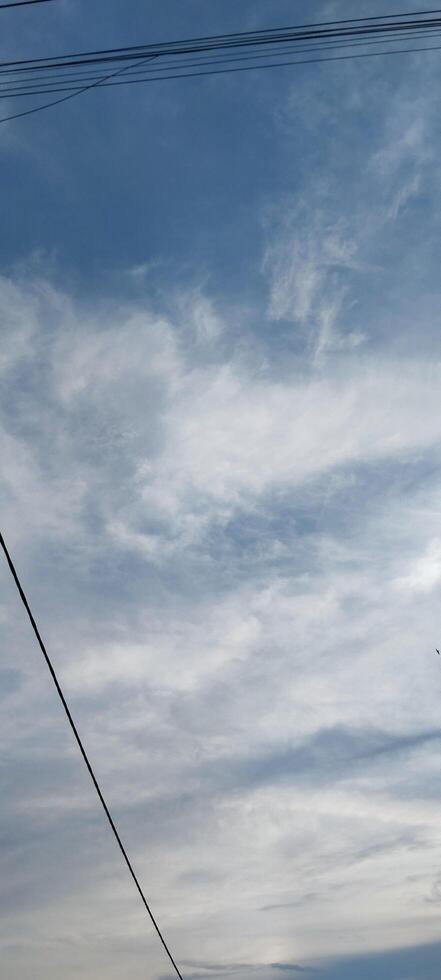 A plane flying in the sky with a few clouds photo