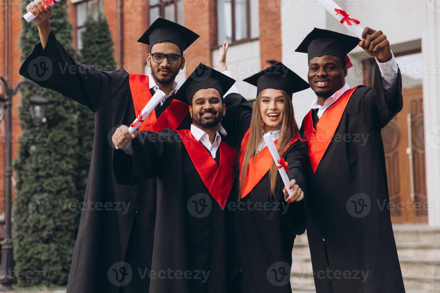 Group of Diverse Happy Graduates Celebrating Achievement Outside University in Cap and Gown photo