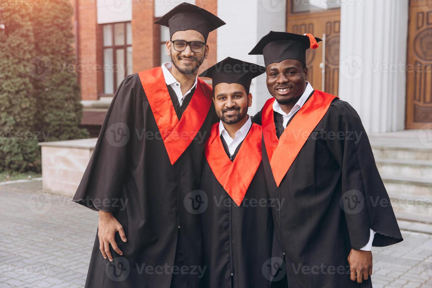 Group of Happy Graduates in Cap and Gown Celebrating Graduation Day Outdoors on Campus photo