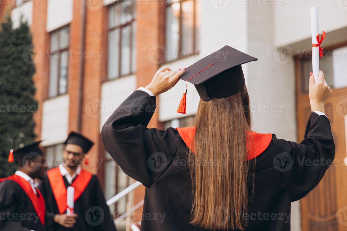 Back View Joyful Group of Graduates Celebrating Outside University Building with Diplomas and Caps photo