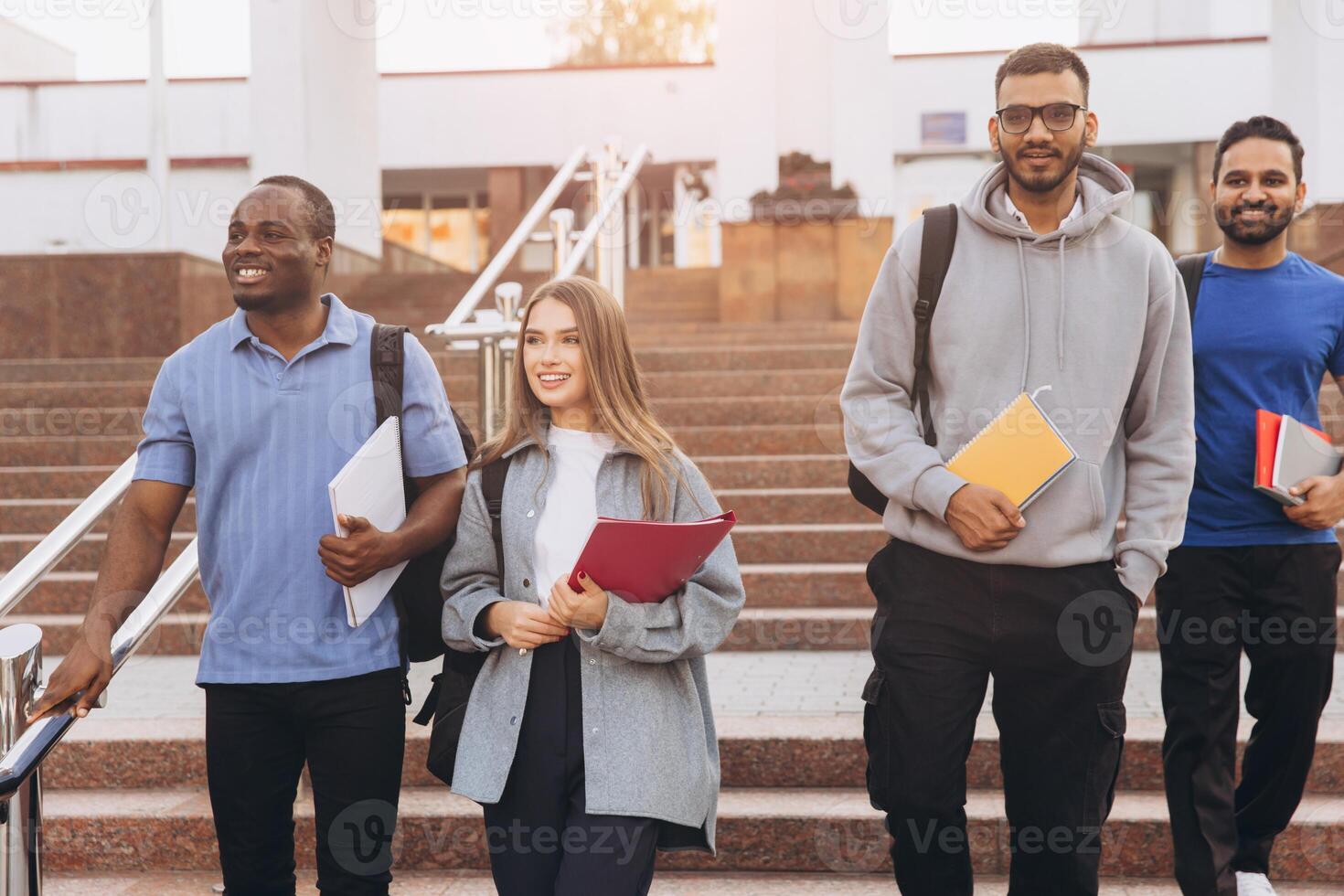 Diverse Group of College Students Walking Together on Campus Stairs Smiling and Holding Notebooks photo