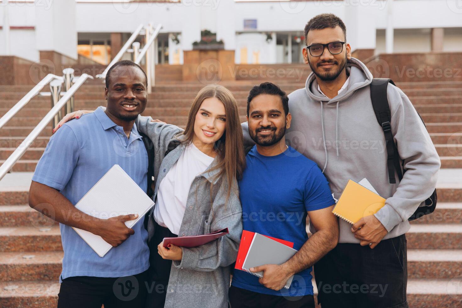 Diverse Group of Happy University Students Posing Together on Campus Steps Holding Notebooks photo