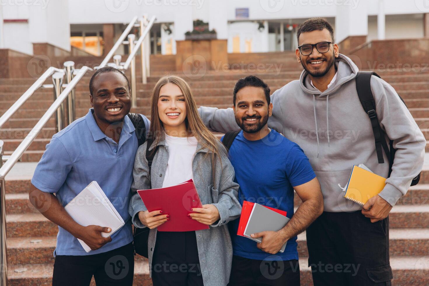 Diverse Group of Happy University Students Posing Together on Campus Steps Holding Notebooks photo