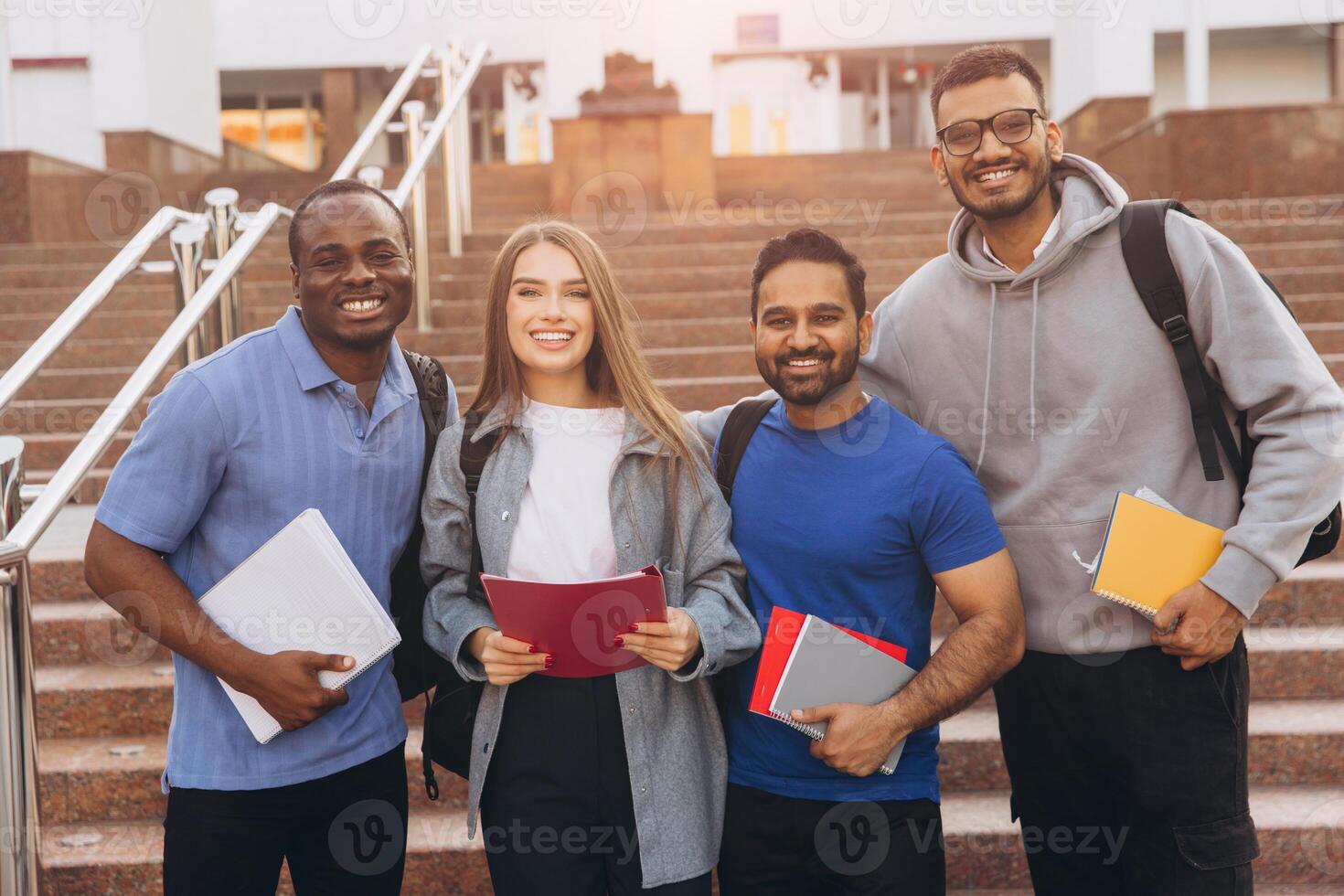 Diverse Group of College Students Smiling Together with Notebooks Outdoors on Campus Steps photo