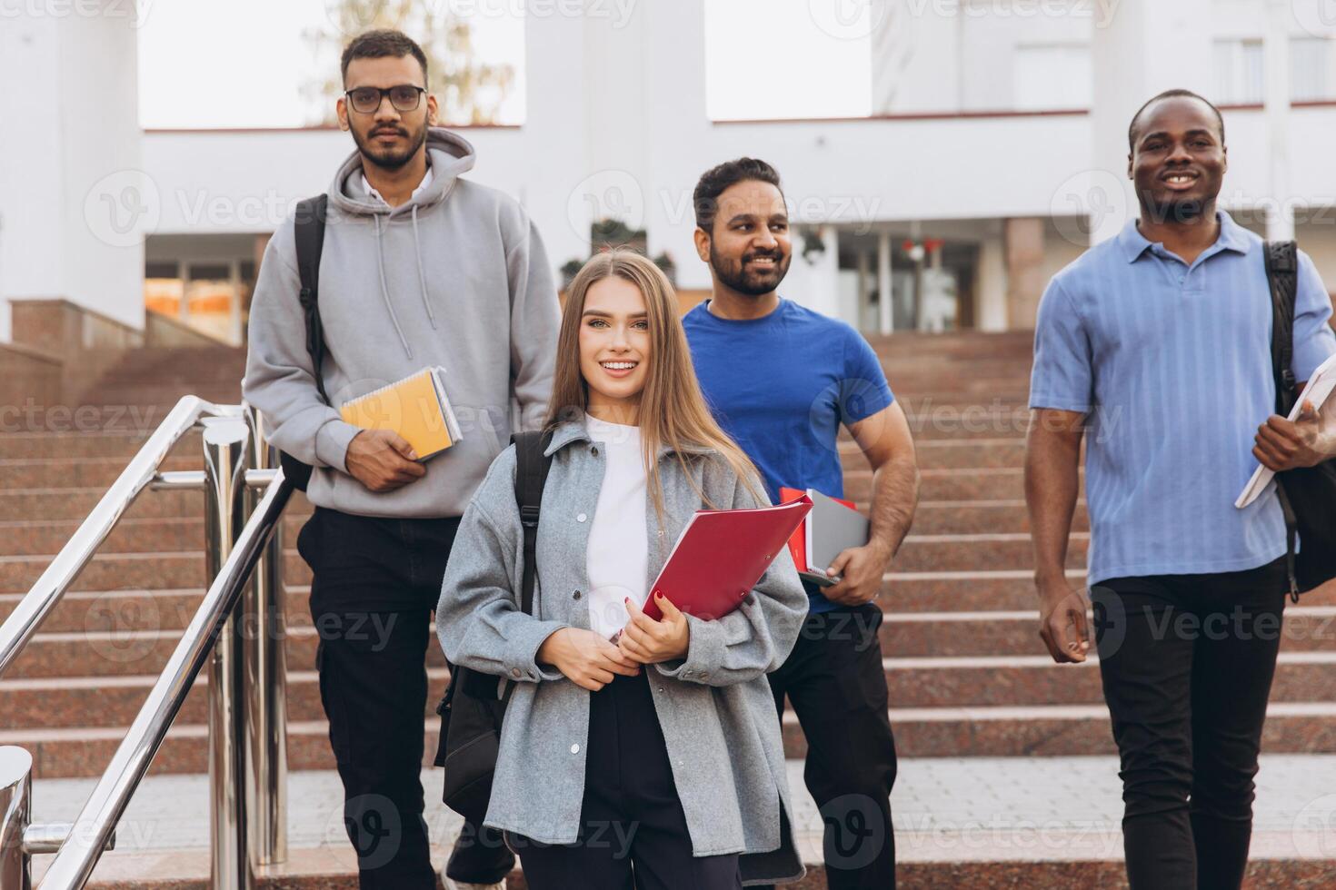 Diverse Group of Smiling College Students Walking on Campus Stairs with Backpacks and Books photo