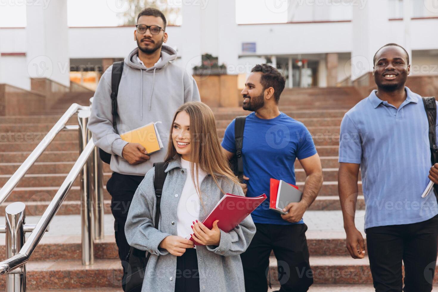 Diverse Group of Smiling College Students Walking on Campus Stairs with Backpacks and Books photo