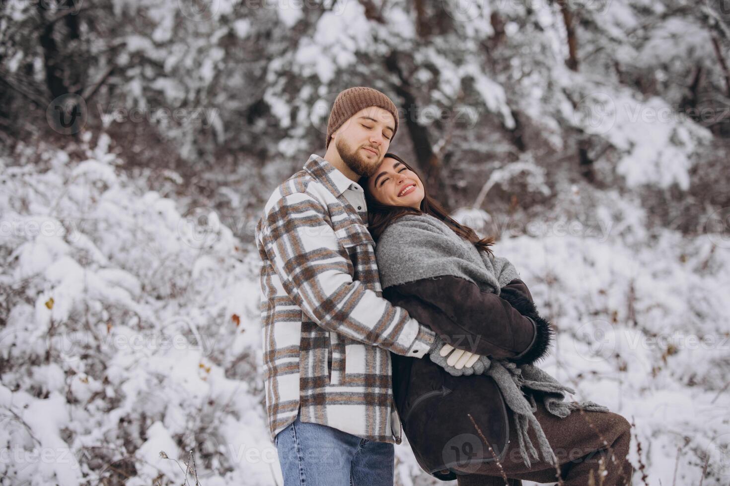 A young happy and loving couple walking in a snowy forest in the mountains photo