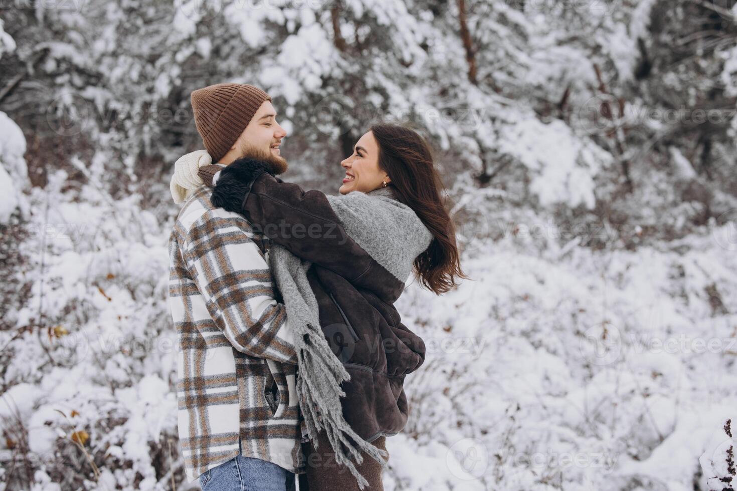 Portrait of a young happy and loving couple having fun in a snowy forest photo