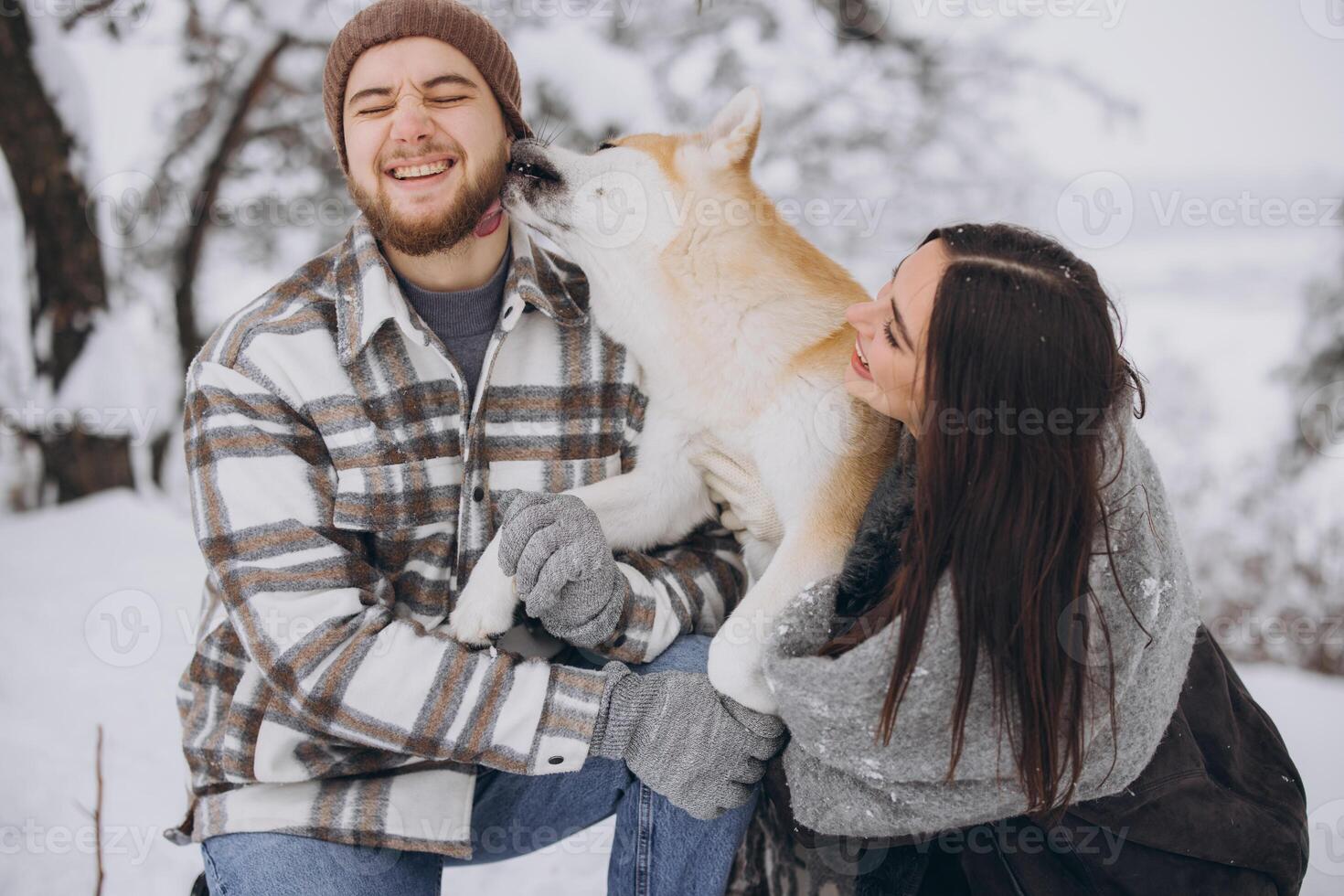 Happy young couple walking with akita dog in forest on winter and snowly day photo