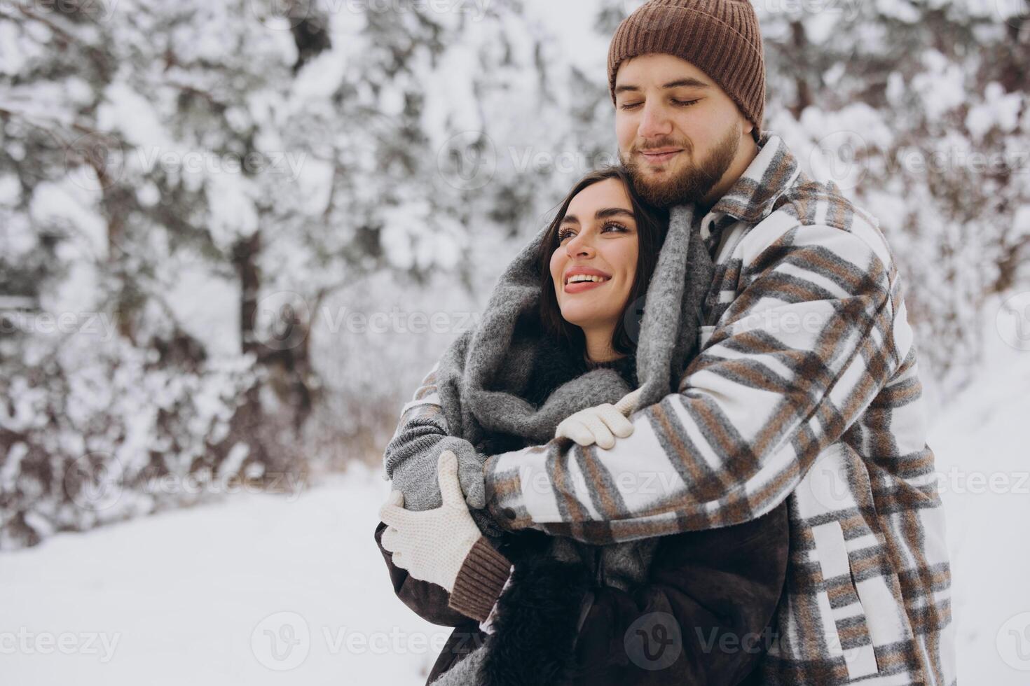 A young happy and loving couple is having fun in a snowy forest in winter. photo