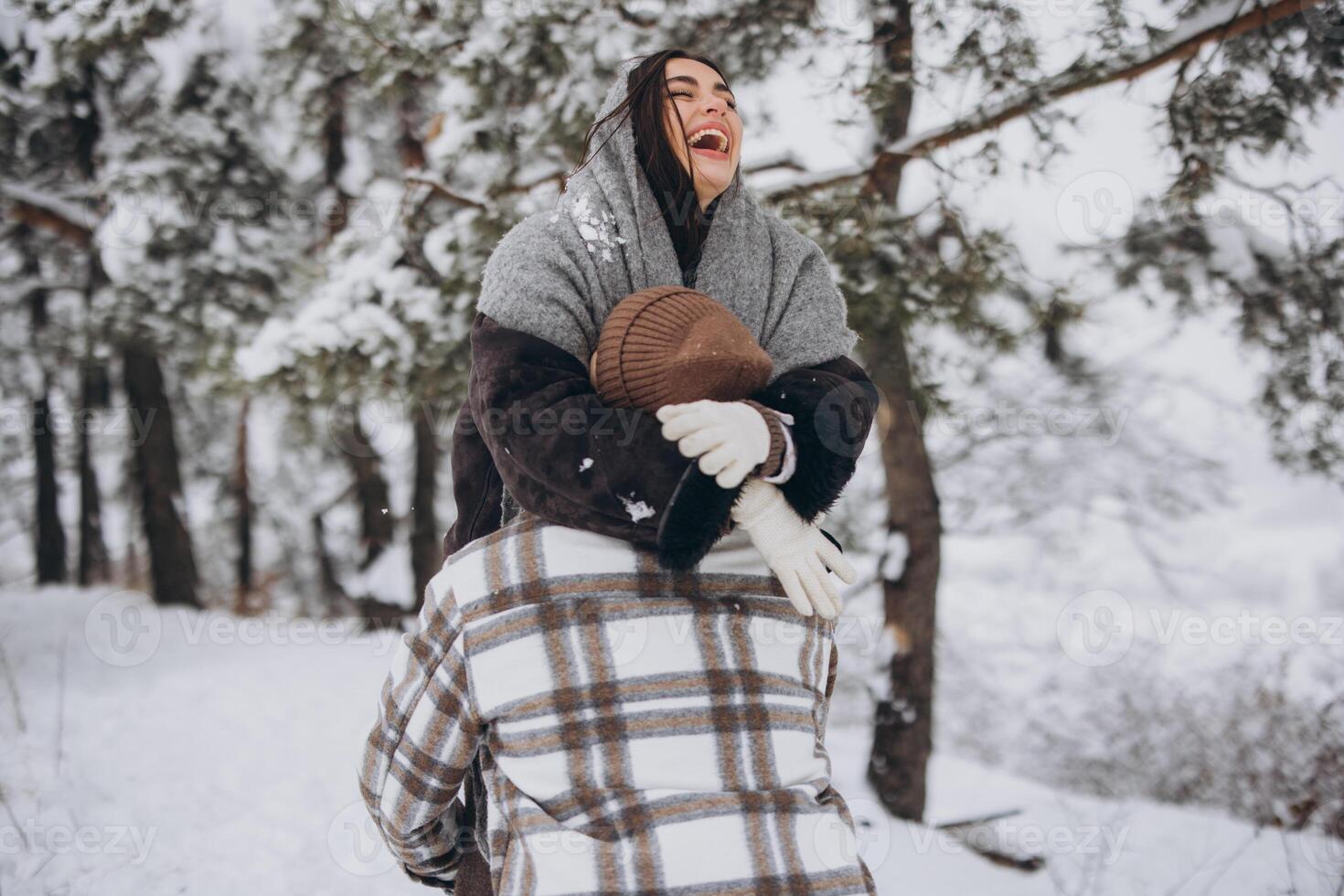 A young happy and loving couple walking in a winter snowy forest in the mountains photo