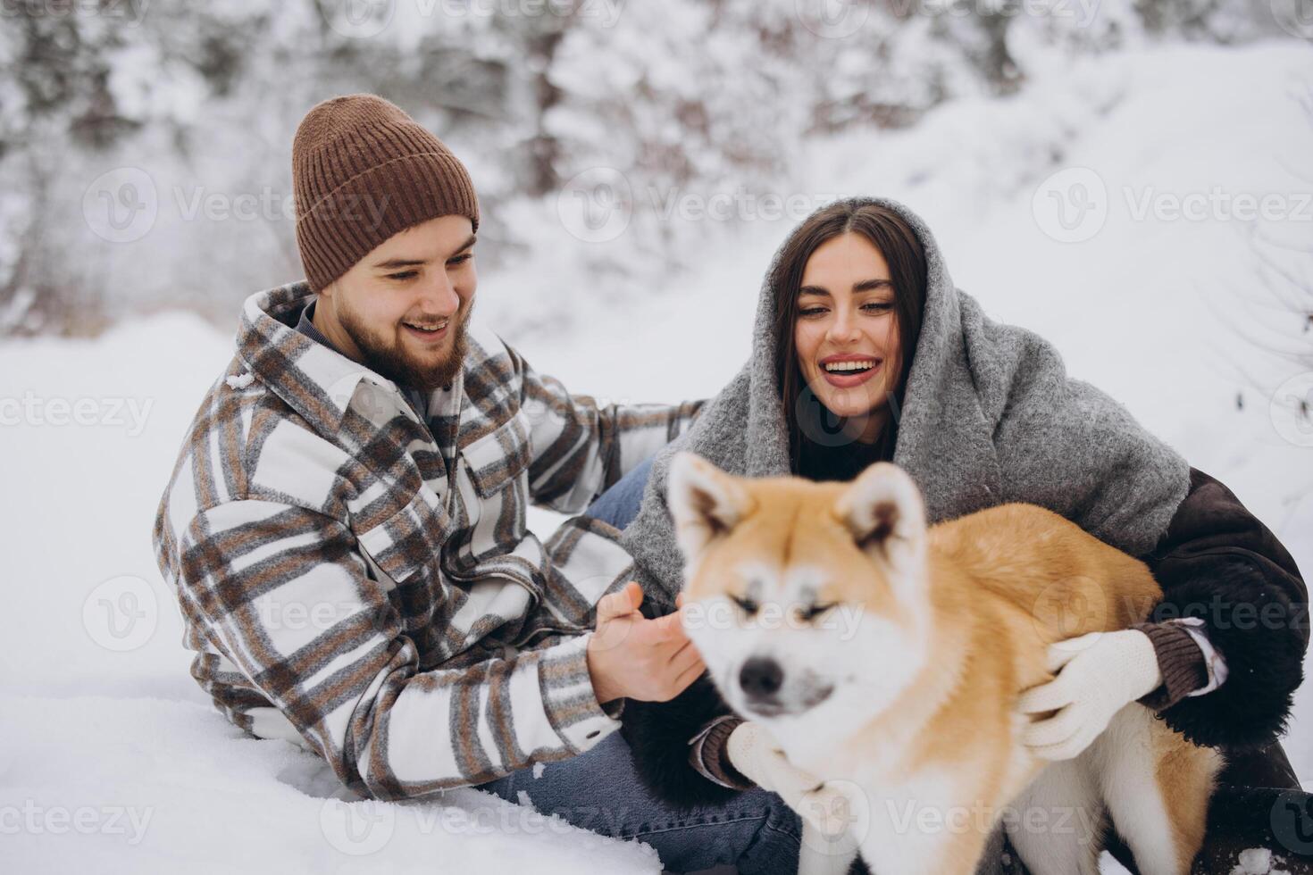 Happy young couple with akita dog in forest on winter day photo