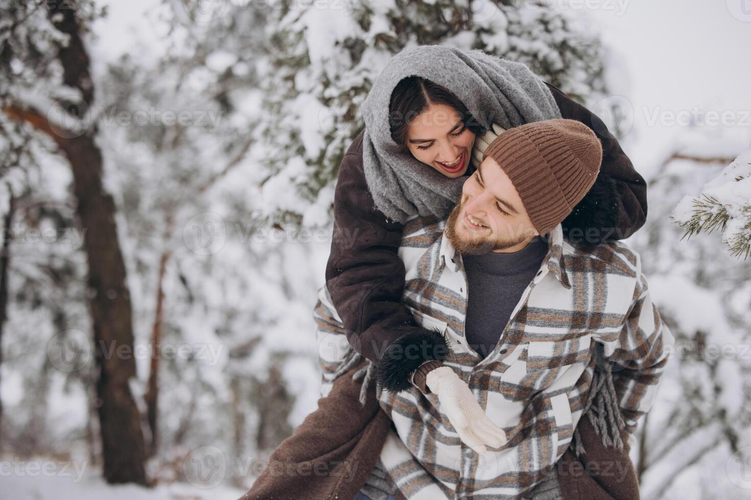 A young happy and loving couple is having fun in a snowy forest in winter. photo