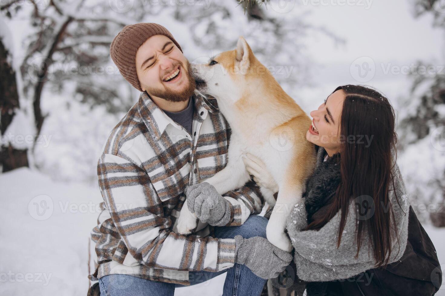 Happy young couple walking with akita dog in forest on winter and snowly day photo