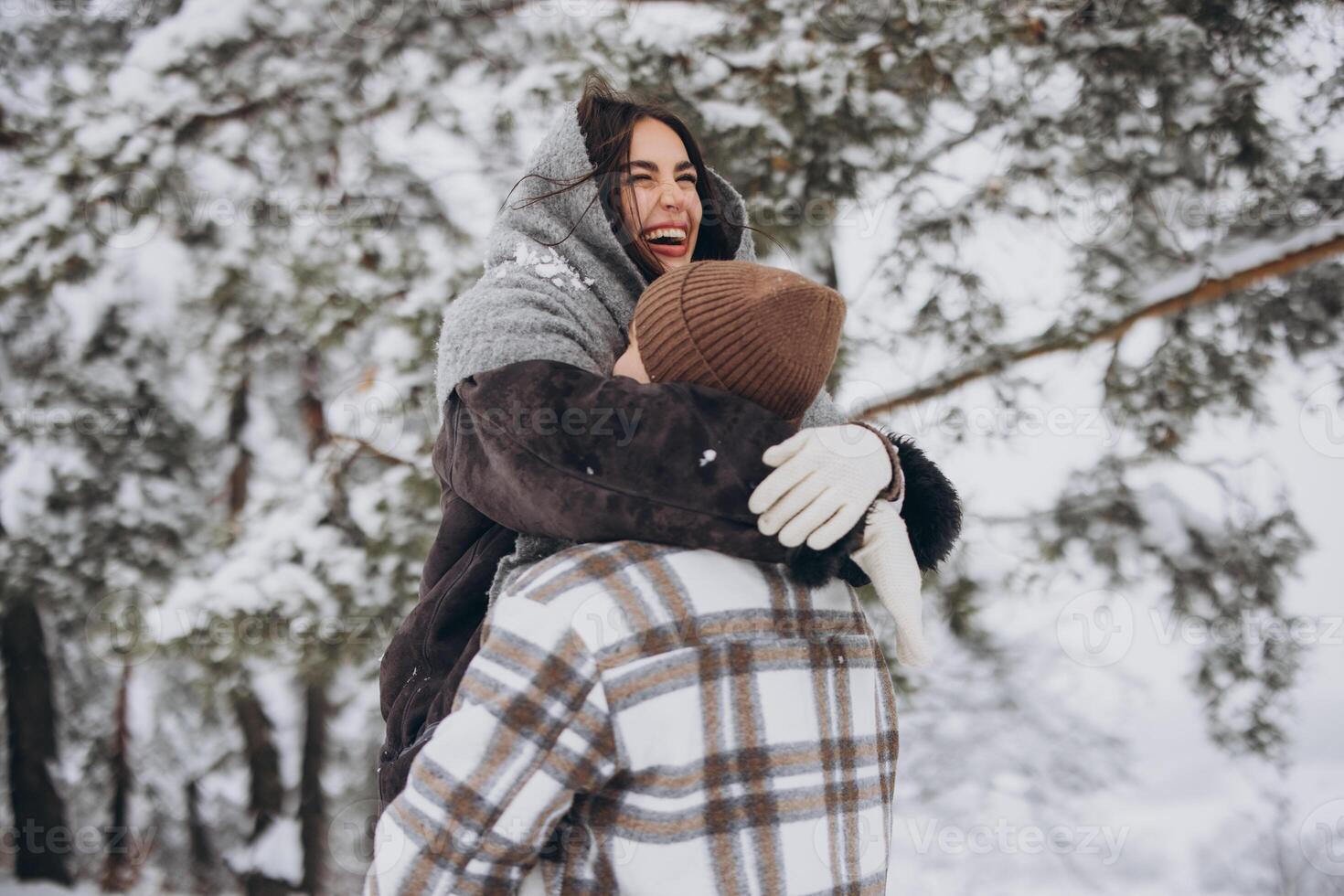 A young happy and loving couple walking in a winter snowy forest in the mountains photo
