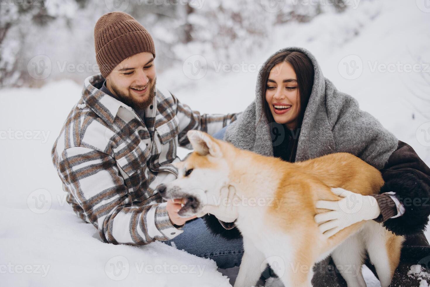 Happy young couple with akita dog in forest on winter day photo