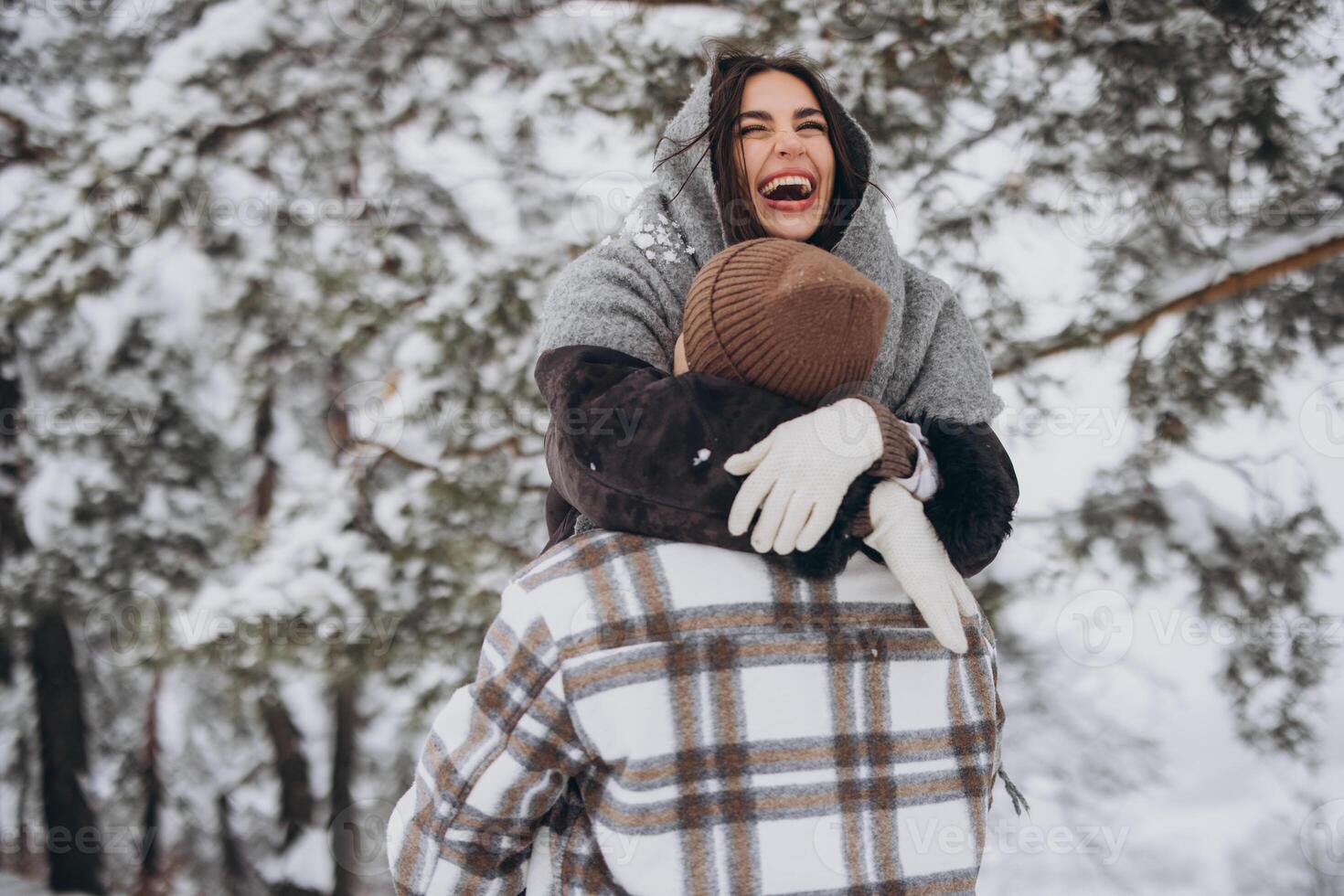 A young happy and loving couple walking in a winter snowy forest in the mountains photo