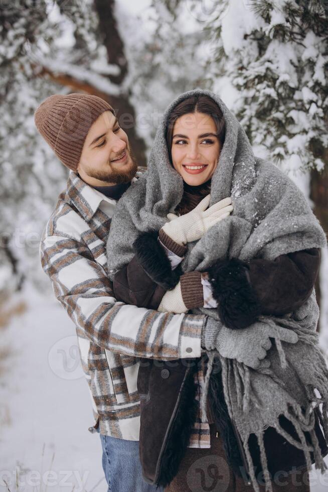 Portrait of a young happy and loving couple having fun in a snowy forest photo