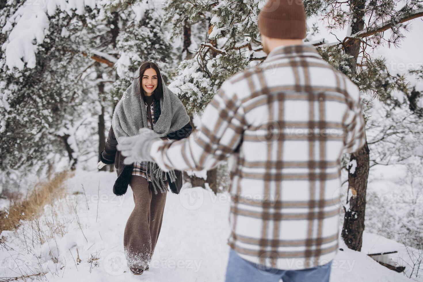 A young happy and loving couple walking in a winter snowy forest in the mountains photo