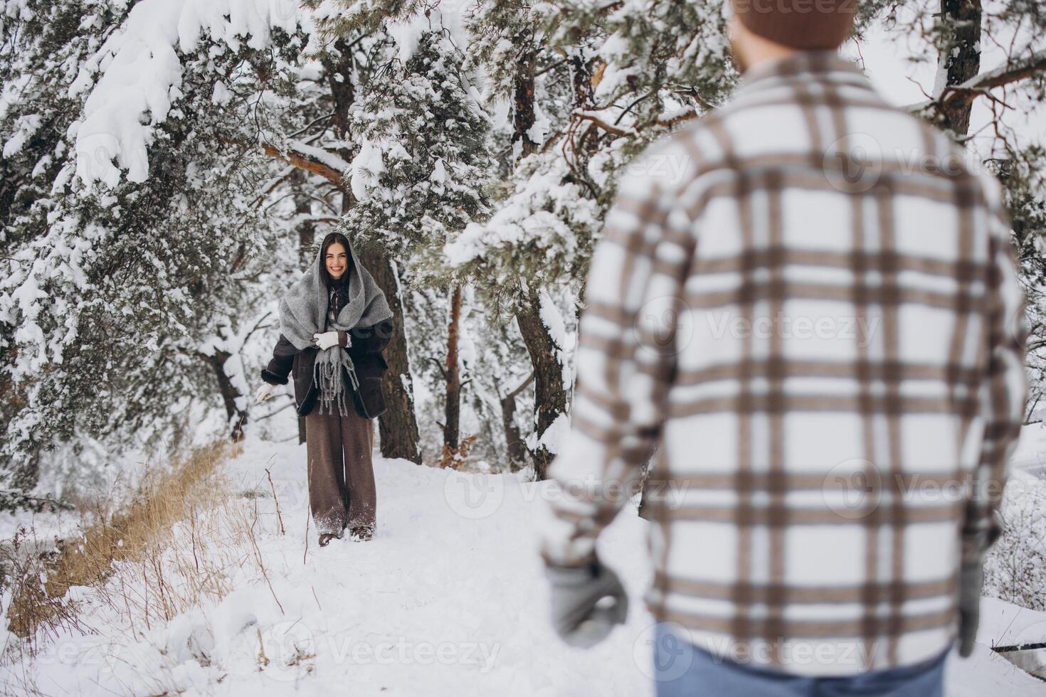 A young happy and loving couple walking in a winter snowy forest in the mountains photo