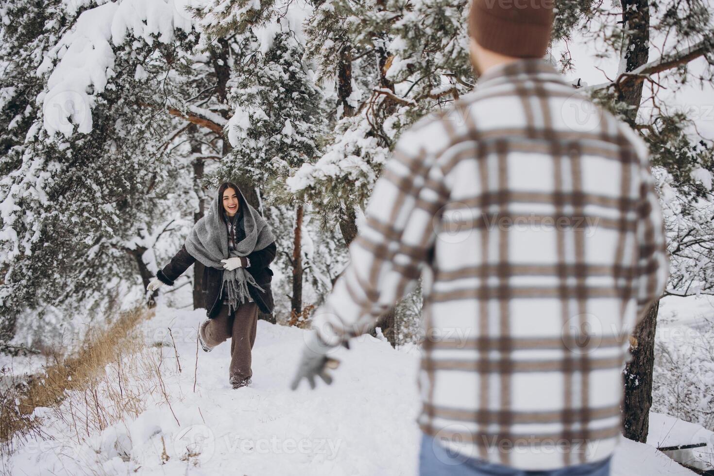 A young happy and loving couple walking in a winter snowy forest in the mountains photo