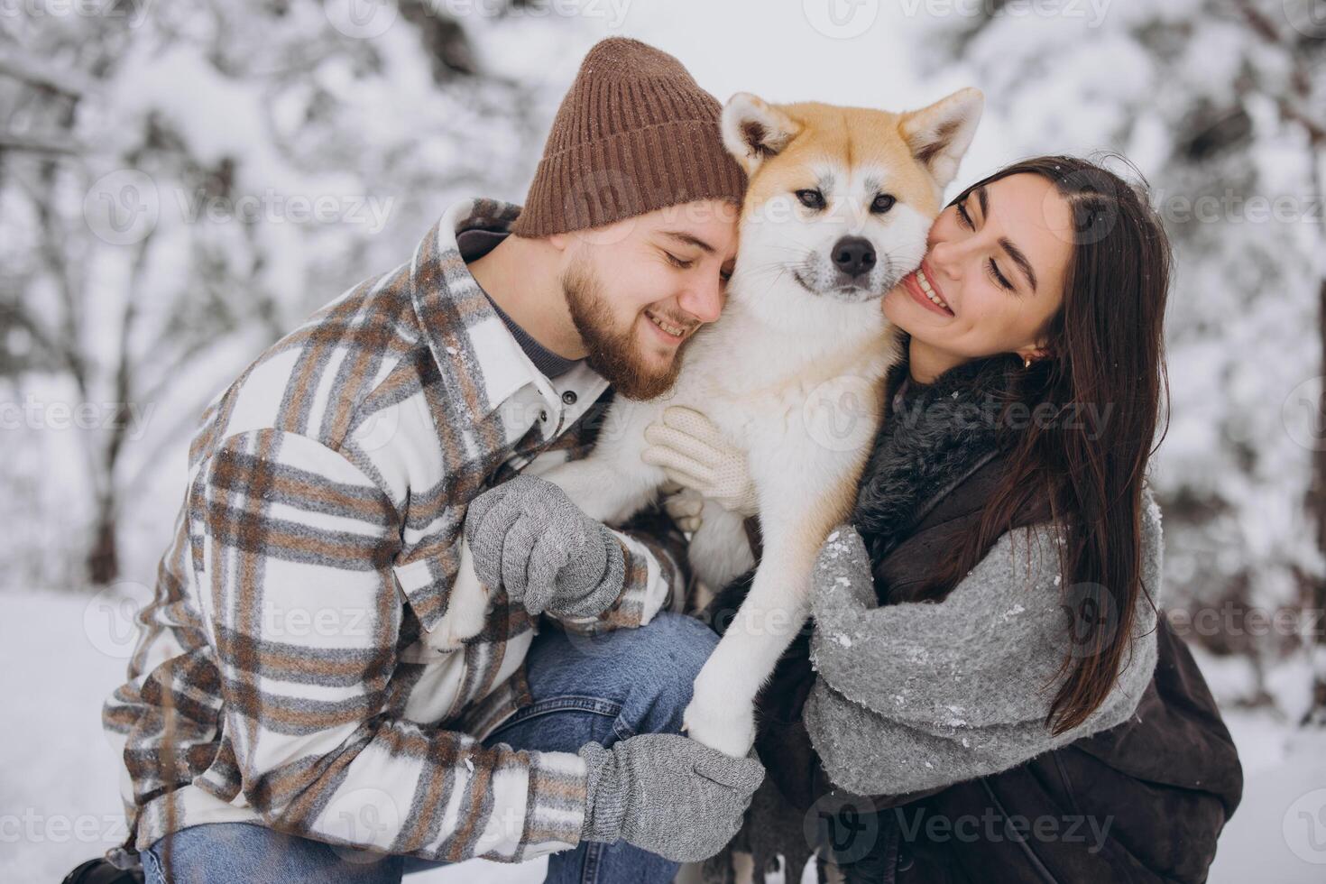 Happy young couple walking with akita dog in forest on winter and snowly day photo