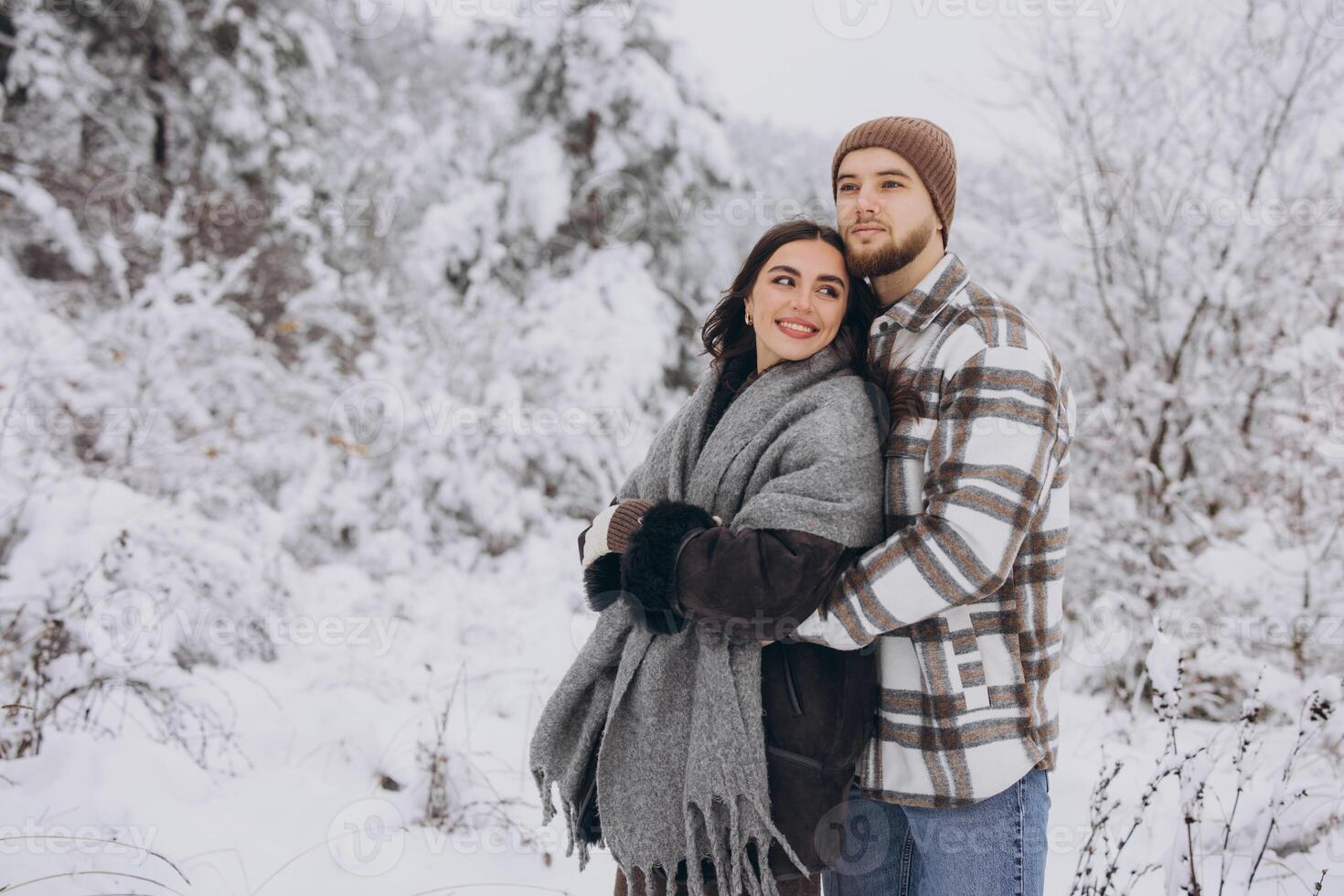 Portrait of a young happy and loving couple having fun in a snowy forest photo