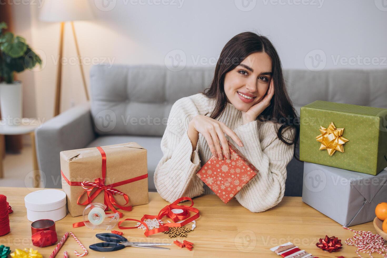 Beautiful happy woman is wrapping and holding Christmas presents at home photo