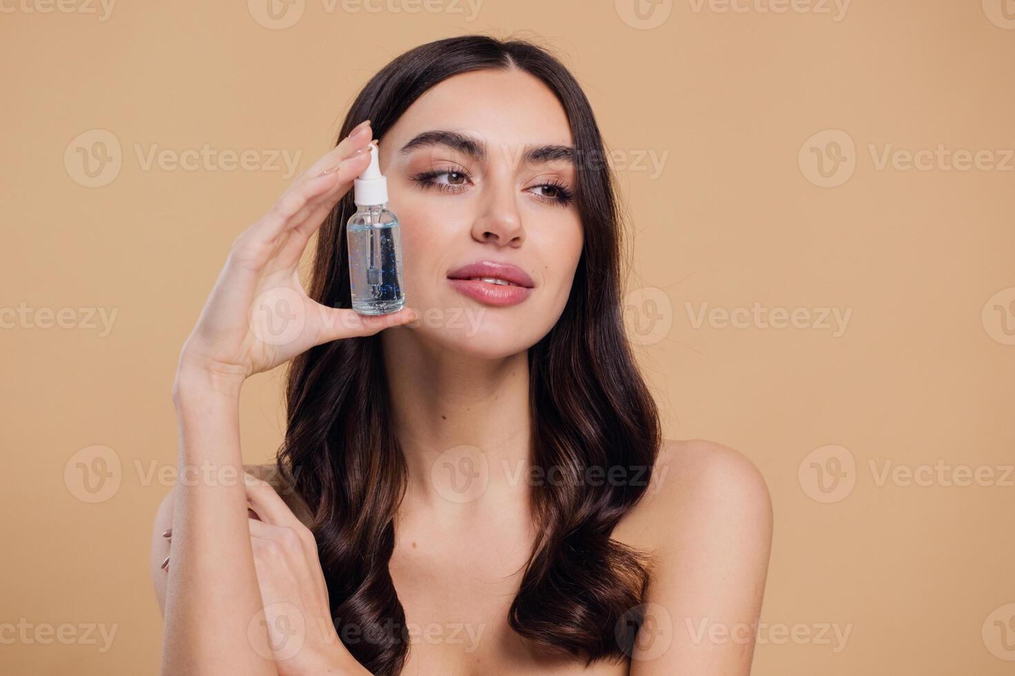Woman Dropping Serum on Face on Beige Background photo