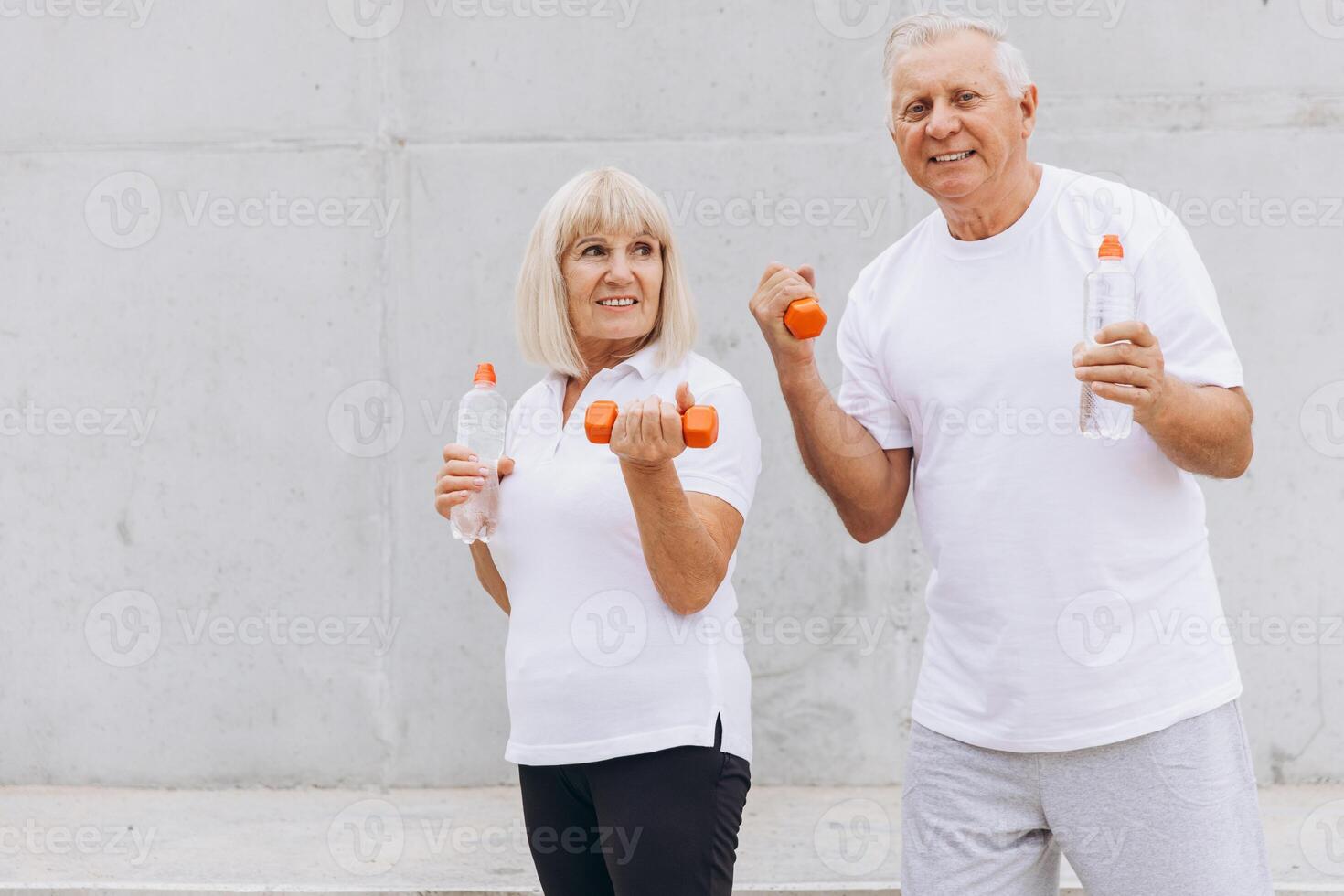 Senior Couple Exercising with Dumbbells and Water Bottles Outdoors photo