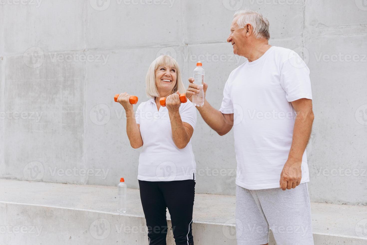 Happy Senior Couple Exercising Outdoors with Dumbbells and Drinking Water photo