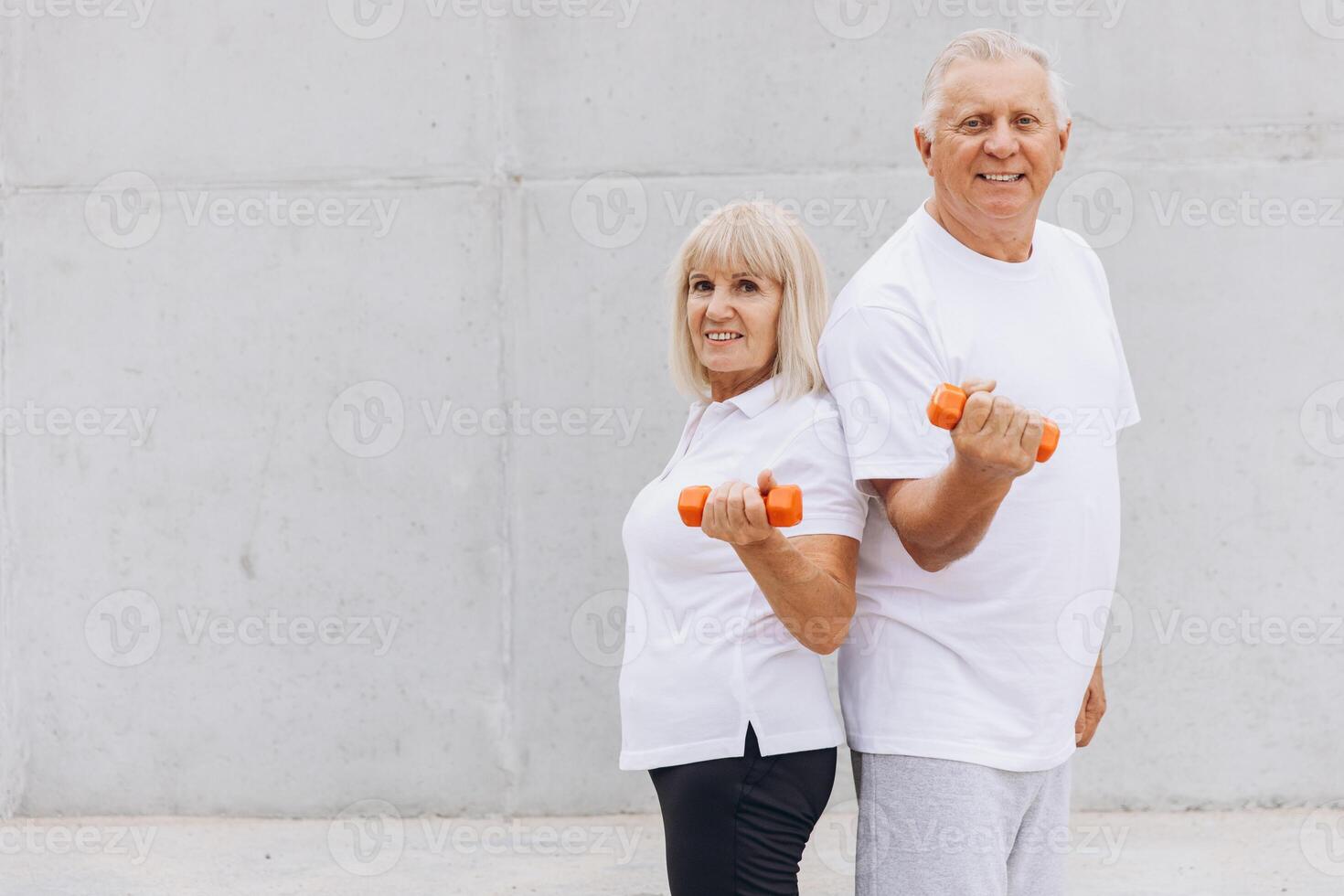 Senior Couple Exercising with Dumbbells Outdoors in Matching White T-Shirts photo