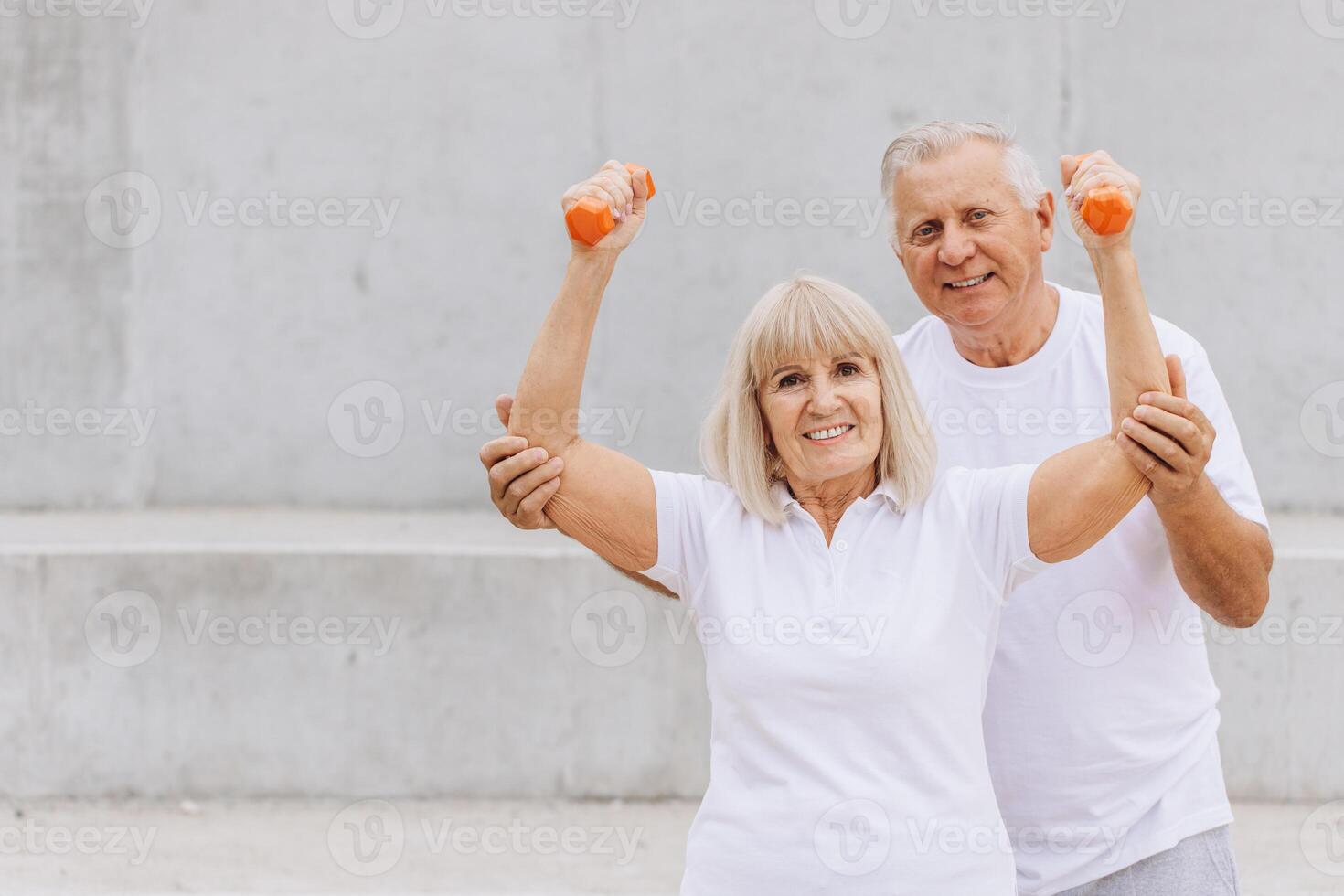 Happy Senior Couple Exercising with Dumbbells Outdoors in Matching White T-shirts photo