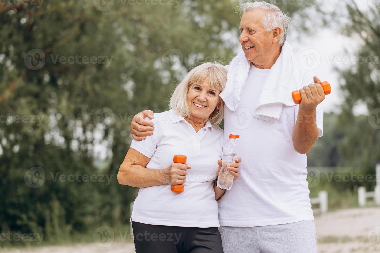 Happy Senior Couple Exercising Outdoors with Dumbbells and Water Bottles photo