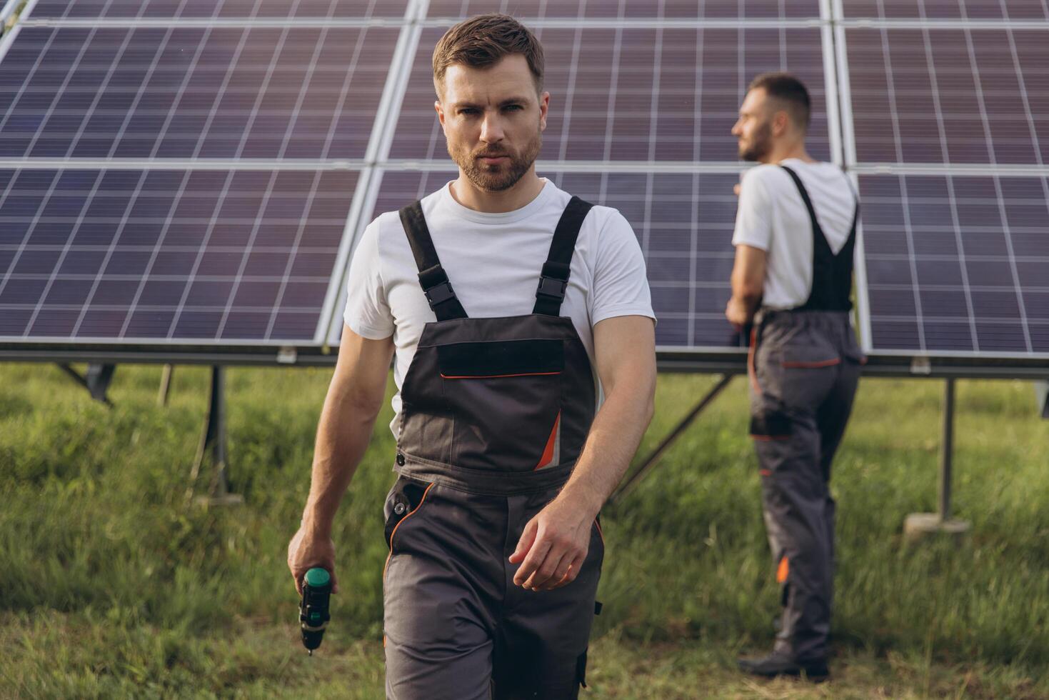 Two skilled workers or craftsmen wearing working gray uniforms, technicians are installing solar panels on a solar farm for clean energy and electricity supply photo