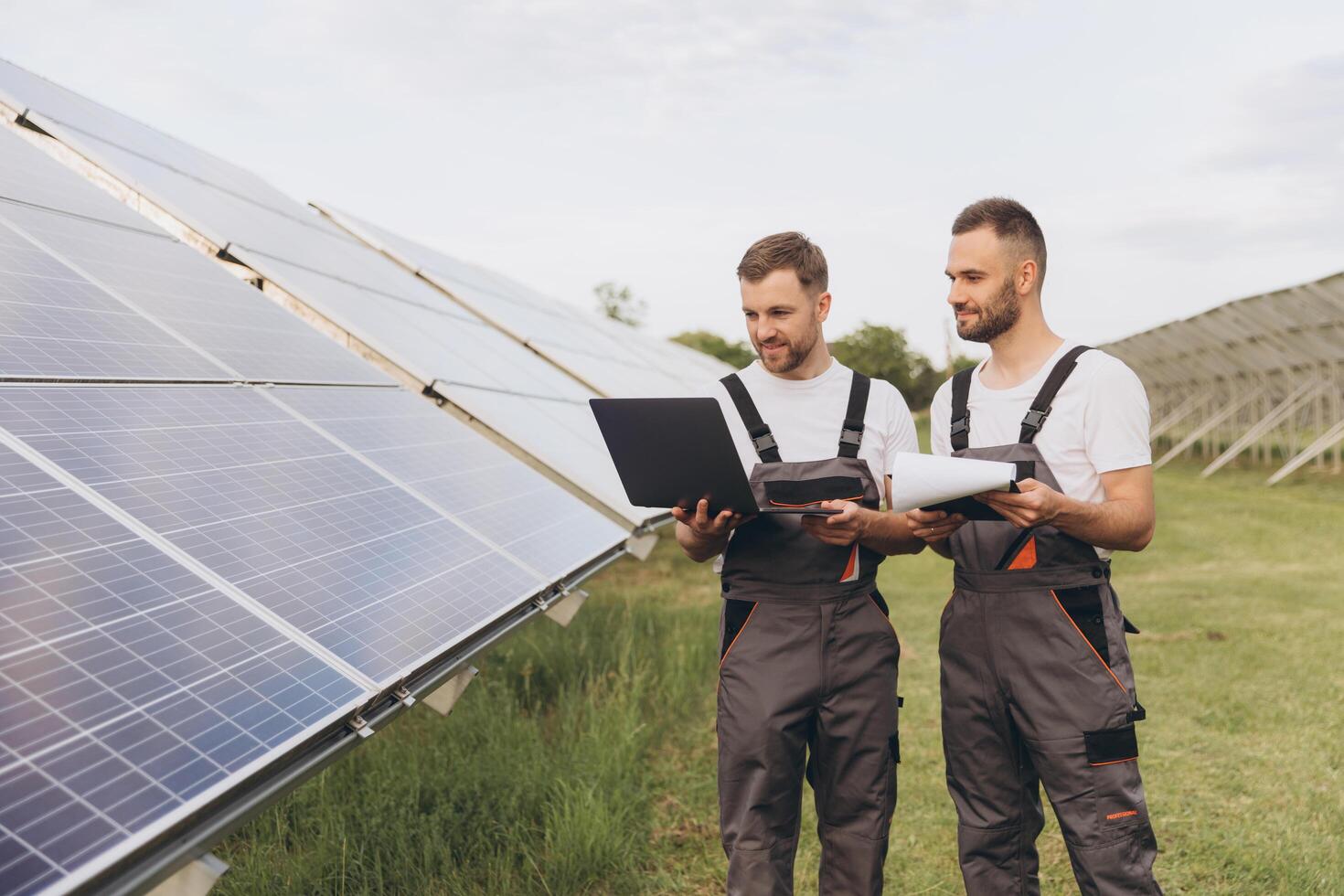 Energy specialist using digital tablet reading information to check the efficiency of solar panel construction. Green energy jobs. Technology. Two solar power plant workers are recording data photo