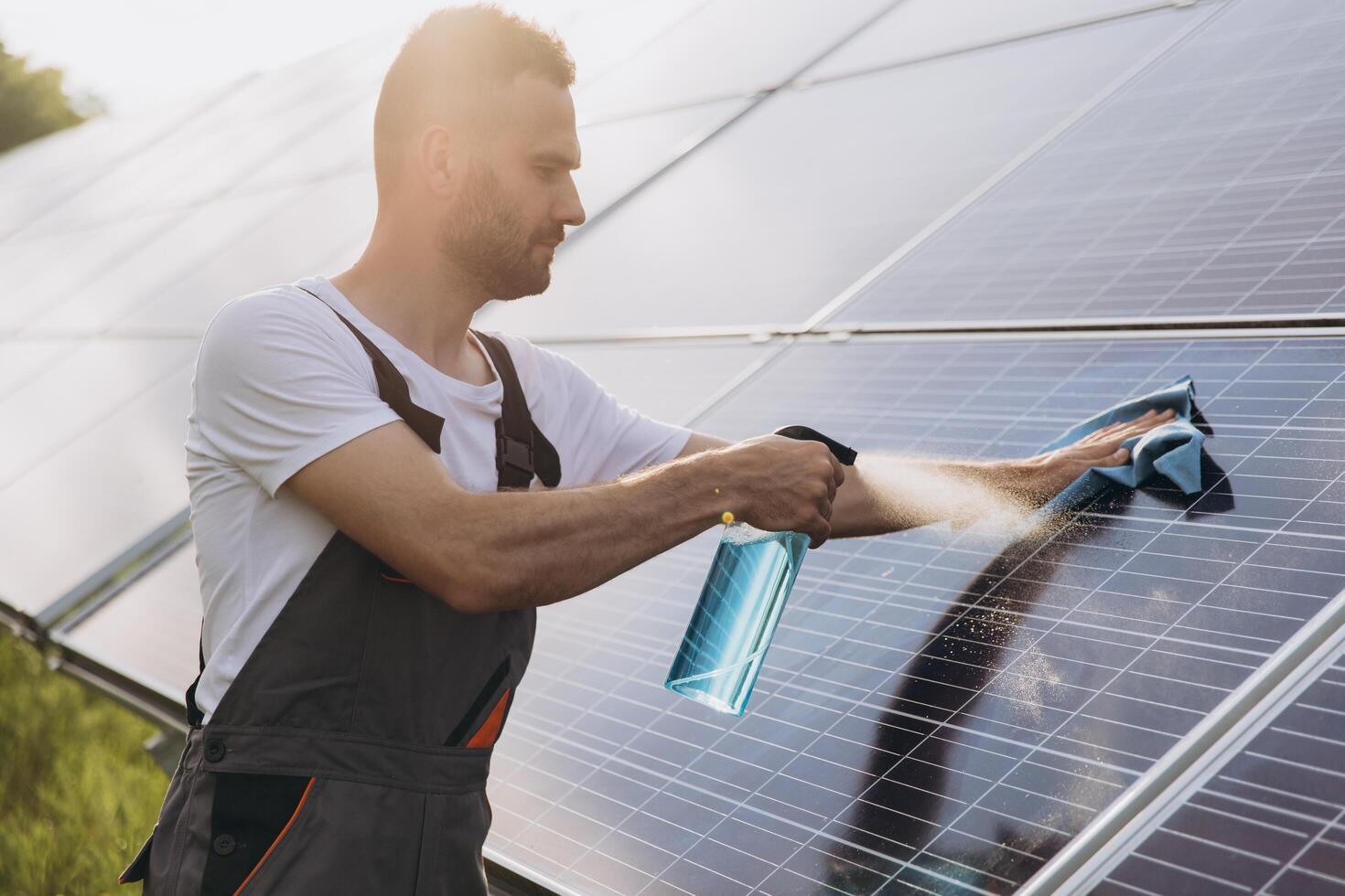 Close-up of a worker cleaning solar panels at a solar power plant or farm, spraying detergent, professional cleaning, solar panels. photo